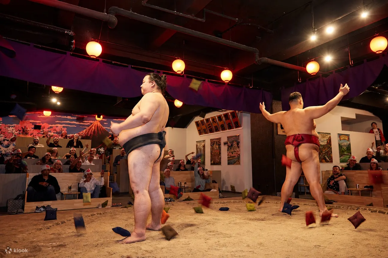 Sumo wrestlers performing before guests seated around the dohyo
