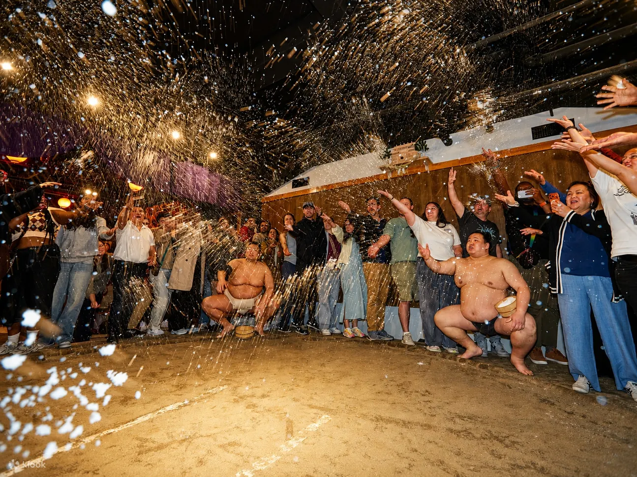Sumo wrestlers and guests throwing ceremonial salt around the dohyo